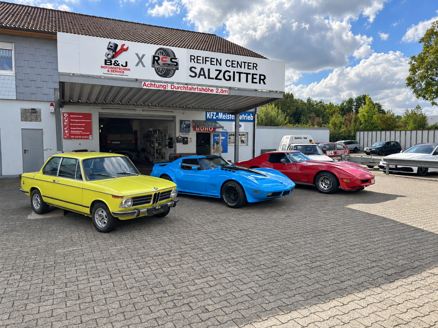 Klassischer BMW und zwei Corvette vor unserer Werkstatt aus seitlichem Blickwinkel